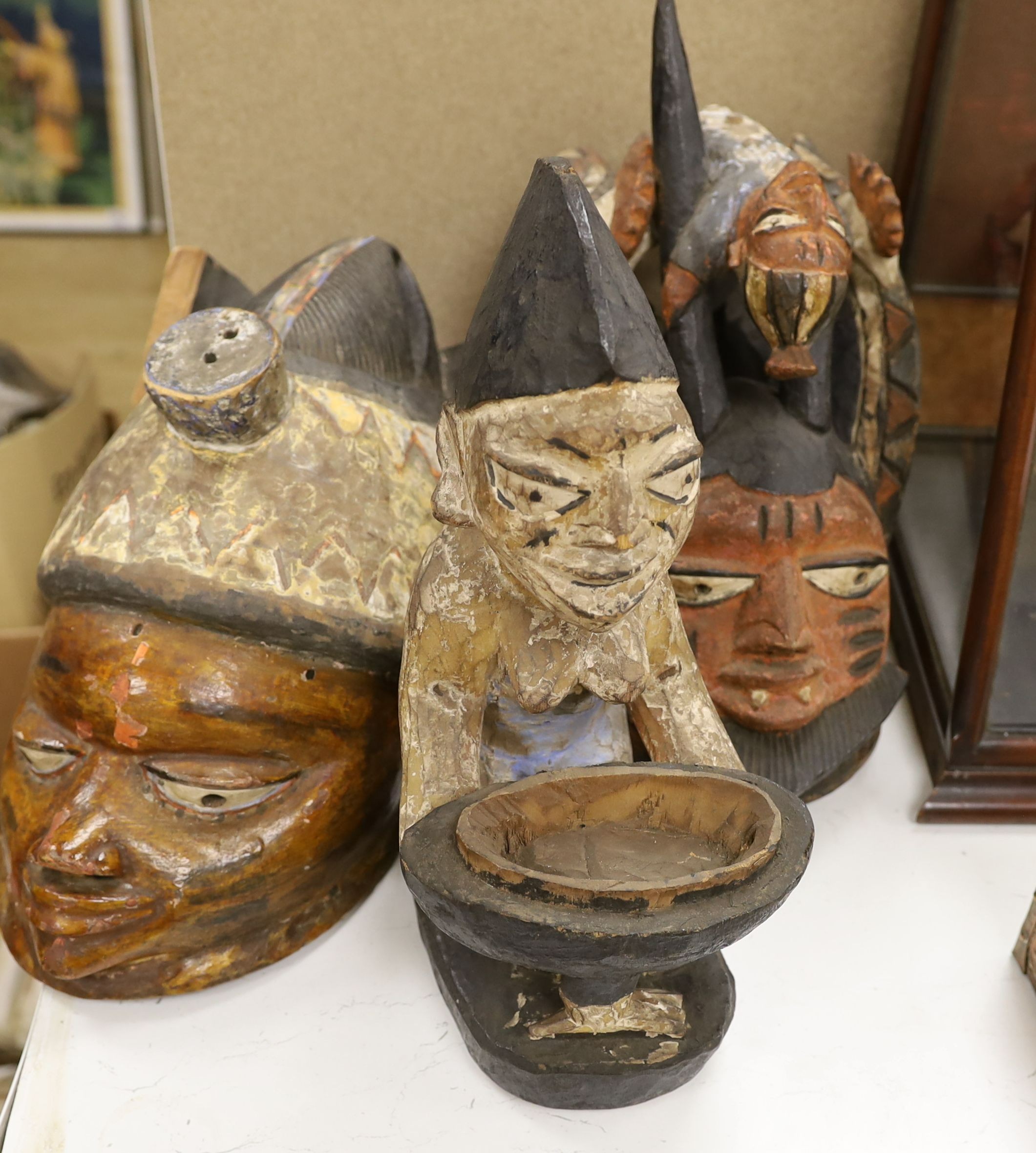 A group of West African tribal artefacts, including a Cross River Egungun mask, 48 x 20cm, a Yoruba Gelede helmet mask, 39 x 38cm and a Yoruba offering figure, 35cm, Provenance- collected by the owner’s uncle before 1960